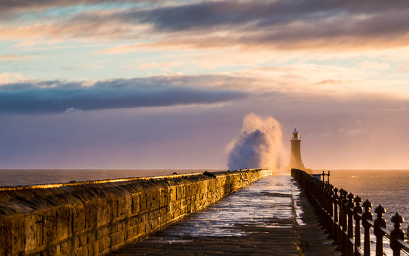 Stormy sea crashing over Tynemouth Pier, Tyneside, Engalnd, UK . In early morning light and sunrise.