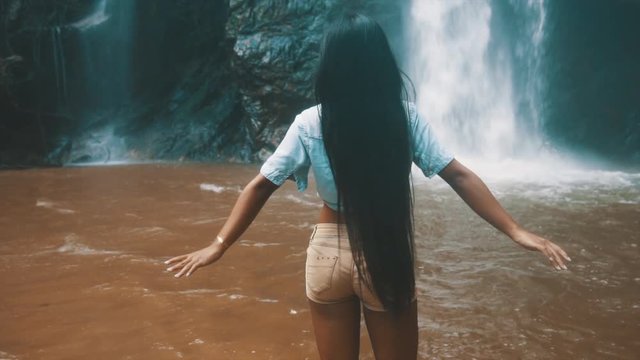 Cinematic 4k SLOW MOTION footage: Active lifestyle travel girl exciting waterfall hidden in the tropical rainforest jungle