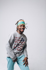 Portrait of a smiling black young model in a gray sweater and blue pants on a gray background