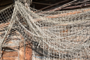 Old fishing nets hanging on a wooden wall. Real, vintage, very old, natural. Old fishnet background. Place for text. Copy space. Real.