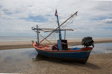 Naklejka premium Fishing boat at the beach of Hua HI on a cloudy day, Thailand,