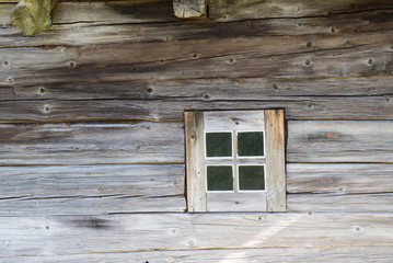 Rustic wooden house made of round logs. Abandoned villages and houses. Ancient window design. Wooden window frame.  Age-old buildings. Closed window. European style. Baltics.