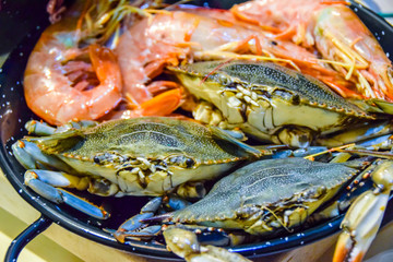lots of raw seafood octopus  shrimp in a frying pan cooking