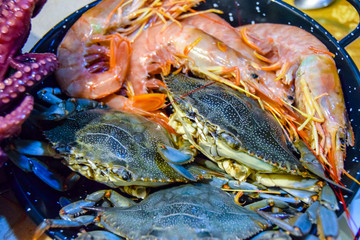 lots of raw seafood octopus  shrimp in a frying pan cooking