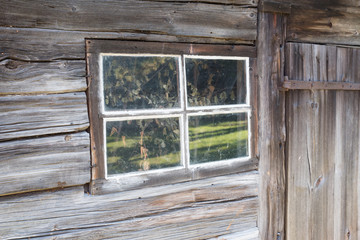 Vintage natural wood wall with small window. Old weathered wooden plank background in gray color. Wood texture, background with natural shadows. Very old house. Place for text. 