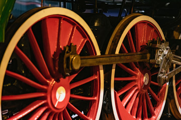 Bright red wheels of old locomotive on railway tracks closeup. Absract vintage background