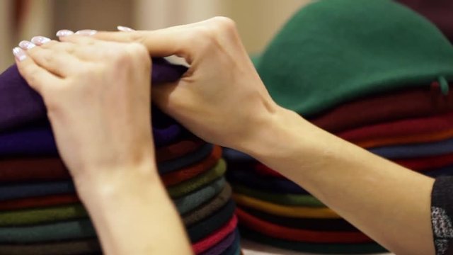 hats - berets of different colors. Women's hands choose a hat