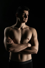 Portrait of a man with a beautiful athletic body in a low key. Pumped up guy with a naked torso.