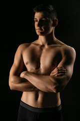 Fototapeta premium Portrait of a man with a beautiful athletic body in a low key. Pumped up guy with a naked torso.