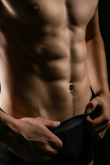 Fototapeta na wymiar pumped handsome male press. Male athletic body closeup on black background.