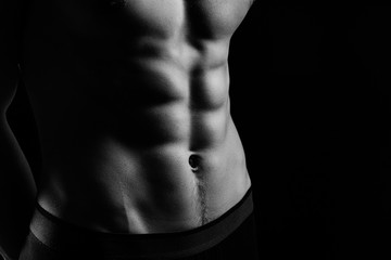 pumped handsome male press. Male athletic body closeup on black background - obrazy, fototapety, plakaty