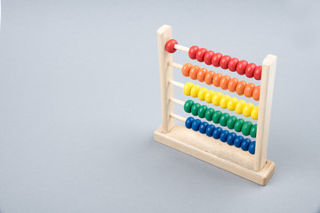 Traditional counts/abacus with colorful wooden beads on gray background. Toy abacus to learn counting. Colorful children counting frame for kids. Counts show: one. Copy space. Top view.