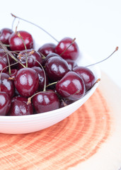 Cherry in a bowl on a white background. The photo shows cherries in a bowl on a white background, macro photo.
