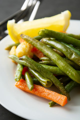 Vegetarian food. Cooked tir, green beans with carrots and lemon, on white plate. Famous Chinese cuisine. Healthy food.