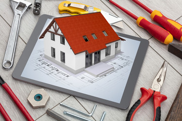 Tablet with construction tools and 3d home plan concept
