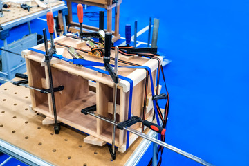 Carpenter work. Gluing the wooden structure. Joiner clamps. Wooden construction under the press. Wooden products to order.