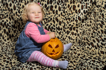 a little blonde girl is interested in two cut for halloween pumpkins