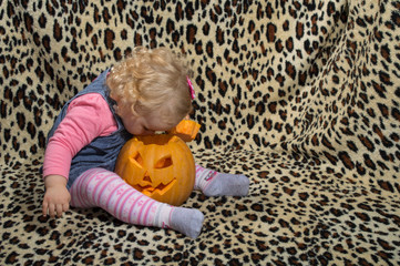 a little blonde girl is interested in two cut for halloween pumpkins