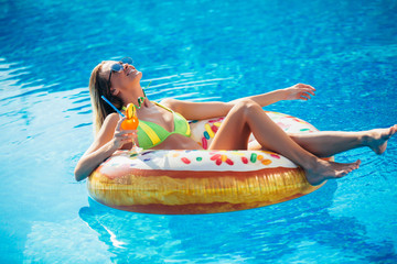 Summer Vacation. Enjoying suntan Woman in bikini on the inflatable mattress in the swimming pool.