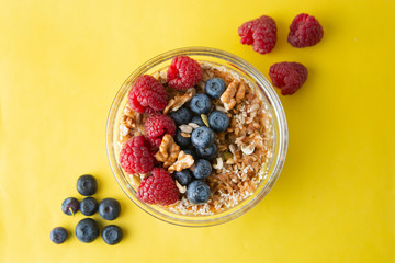 Cereal, muesli granola  and various delicious fruit, berries for breakfast. healthy, energy breakfast, yellow colorful background.