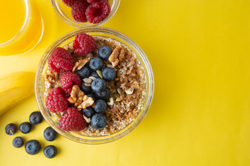 Cereal, muesli granola  and various delicious fruit, berries for breakfast. healthy, energy breakfast, yellow colorful background.