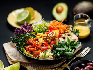 Buddha bowl of mixed vegetables, tofu cheese and groat on a black background. Gourmet and...