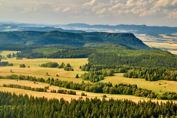 Fototapeta na wymiar View from the Table Mountains in Poland on Slovakian mountains and meadows, a lot of trees. Day is sunny but a little cloudy.