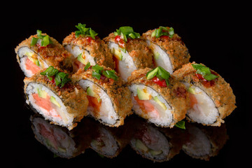 Hot fried Sushi Roll with smoked salmon, scallops, shrimp, avocado and cheese on black background. Sushi menu. Japanese food. 
