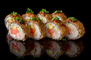 Hot fried Sushi Roll with smoked salmon, scallops, shrimp, avocado and cheese on black background. Sushi menu. Japanese food. 