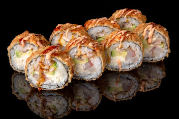 Hot fried Sushi Roll with perch, eel, shrimp, avocado and cheese on black background. Sushi menu. Japanese food. 