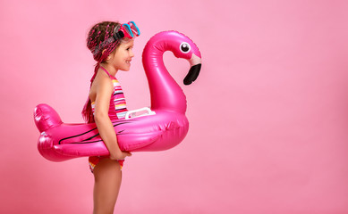happy child girl in swimsuit with swimming ring flamingo on a colored pink background   © JenkoAtaman