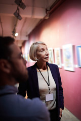 Portrait of two art gallery workers inspecting paintings in museum exhibition