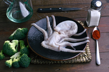 raw octopus in porcelain dish on rustic wood
