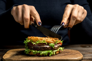 Healthy lifestyle, proper nutrition. Female hands cut a useful rice burger with vegetables, herbs and cutlet on a wooden board