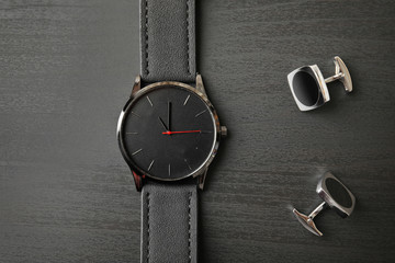 Stylish wrist watch and cuff links on wooden background, top view. Fashion accessory