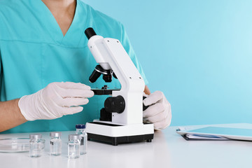 Male doctor using microscope at table, closeup with space for text. Medical object