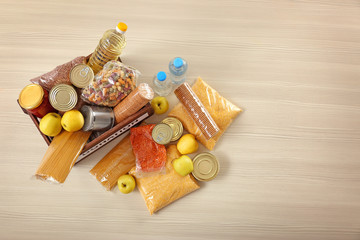 Donation box and different products on wooden table, top view. Space for text