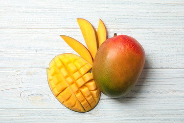 Flat lay composition with ripe mangoes on white wooden background