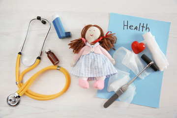 Flat lay composition with doll and medical items on wooden background. Children's doctor