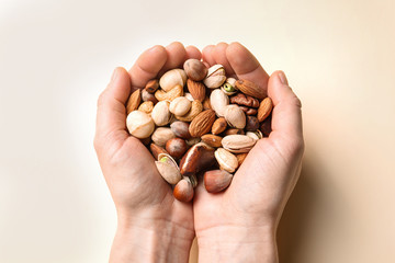 Woman holding organic mixed nuts on color background, closeup