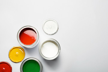 Open paint cans and space for text on grey background, top view