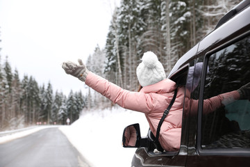 Young woman looking out of car window on road. Winter vacation