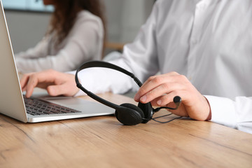 Technical support operator with headset at workplace, closeup