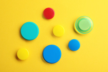 Bright magnets on color background, top view