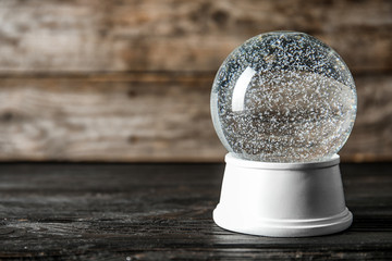 Magical empty snow globe on wooden table. Space for text