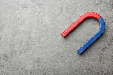 Red and blue horseshoe magnet on grey background, top view with space for text