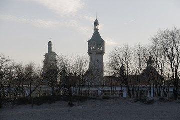 Baltic Sea coast during winter. View from the sandy beach to the lighthouse, evangelical church, Spa House, Spa Square. Tourist attractions. A frosty, calm end of the day. Blue sky in the background. 