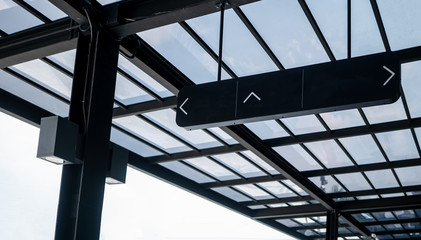 Rectangle directional sign in black color hanging from ceiling.