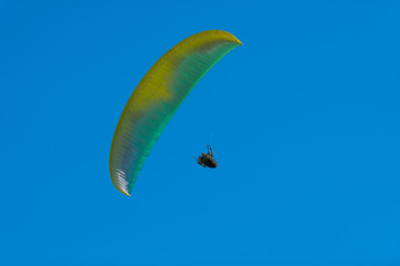 One paraglider flying in the blue sky. Paragliding in the sky on a bright sunny day