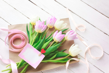 Fototapeta na wymiar International Women's Day. A bouquet of white and pink tulips with a ribbon on a white background. Greeting card. Spring. Selective focus.